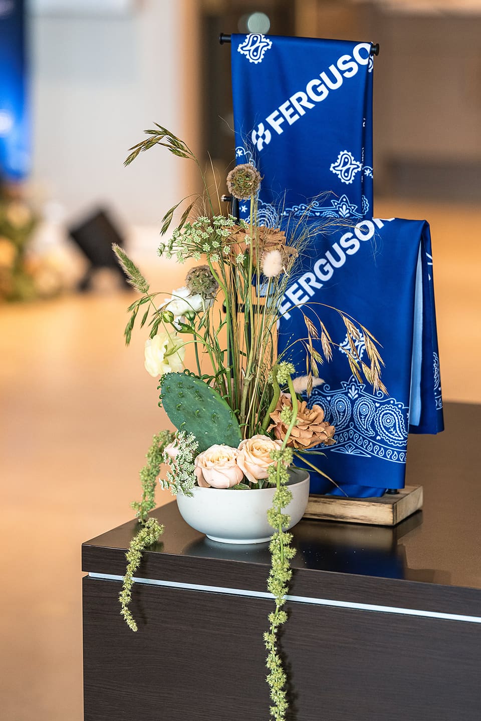 Wild floral arrangement with prickly pear cactus and roses beside a Ferguson branded banner